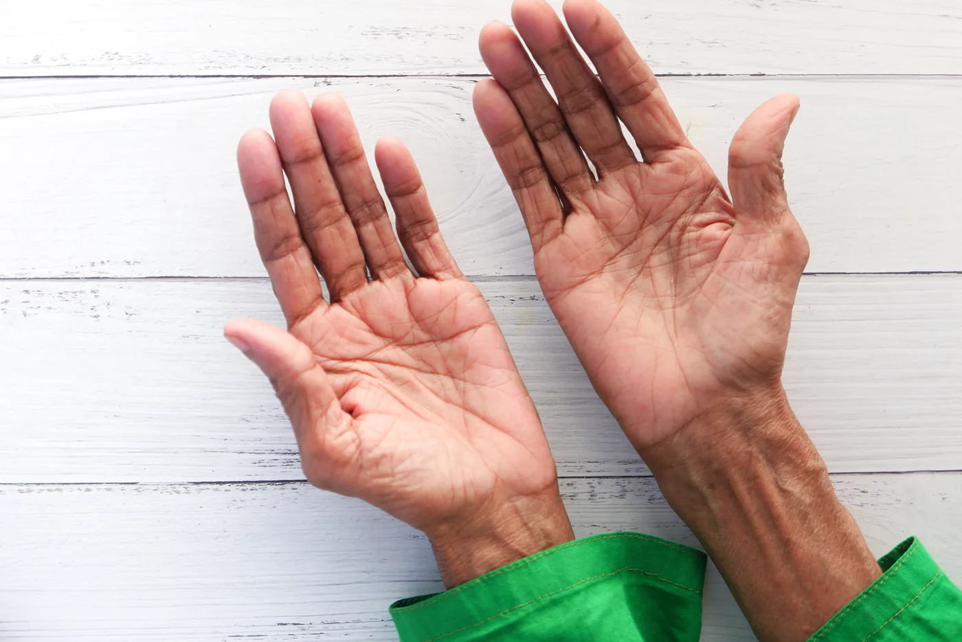A patient laying their hand flat on a table again after private Dupuytren's contracture treatment
