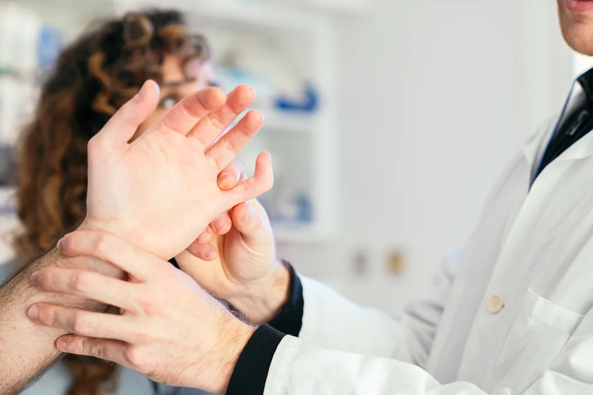 A hand surgeon examining a Dupuytren's cord in a patient's palm