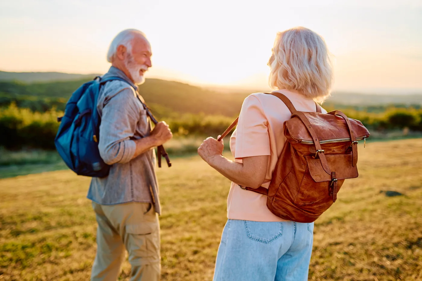 Active older adults hiking outdoors at golden-hour sunset, healthy and mobile after hip replacement surgery