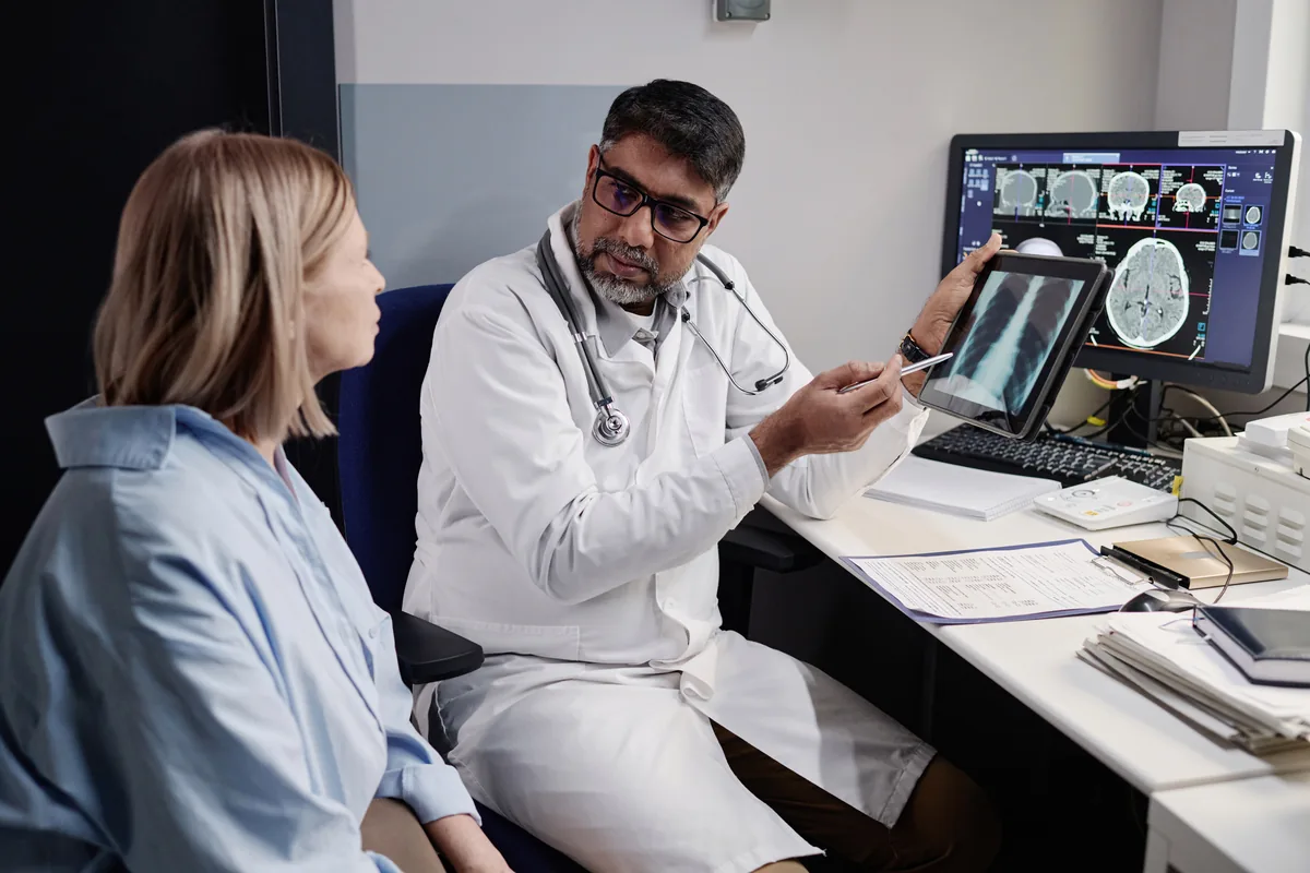 A fellowship-trained surgeon reviewing a scan with a patient at an accredited private facility