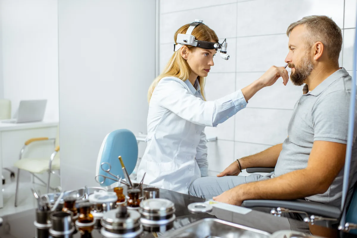 An ENT surgeon examining a patient's nasal septum by endoscopy