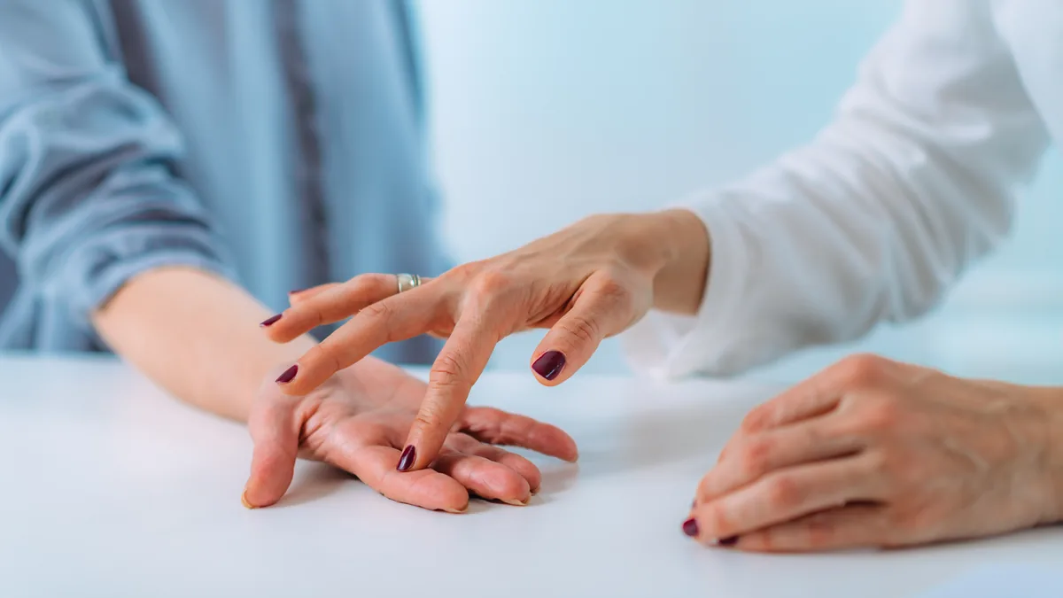 A hand surgeon examining the base of a patient's finger
