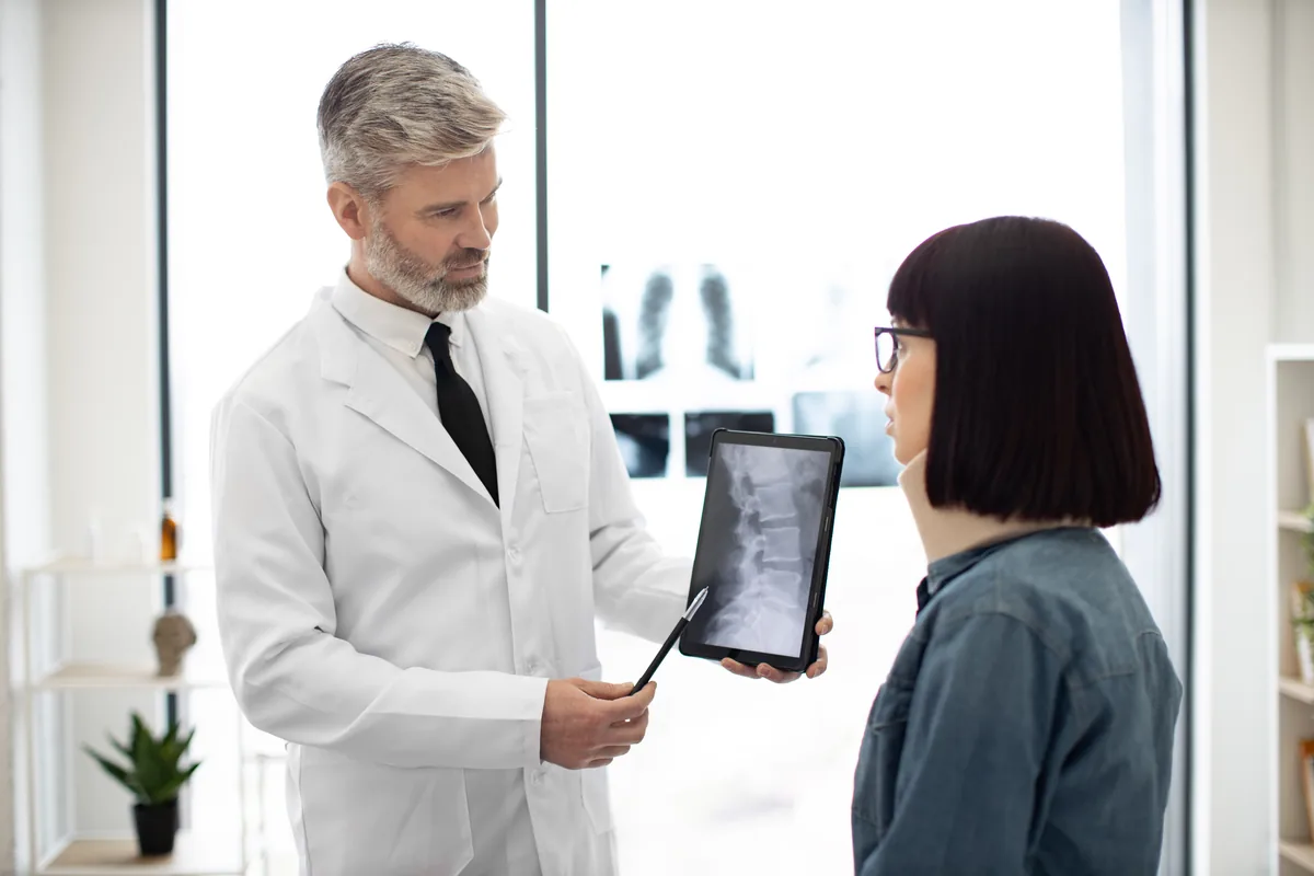 An orthopedic surgeon reviewing a hip x-ray with a patient before hip arthroscopy
